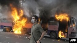 A supporter of defeated Iranian presidential candidate Mir Hossein Musavi stands in front of a burning bus during riots in Tehran.