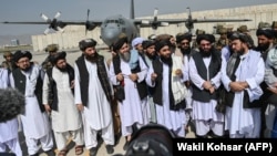 Taliban spokesman Zabiullah Mujahid (center, with shawl) speaks to the media at the airport in Kabul on August 31.