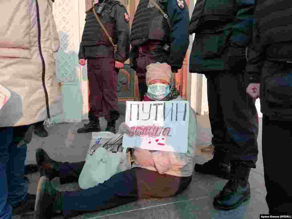 A woman holds a poster reading &quot;Putin is a murderer&quot; during the rally in Omsk.