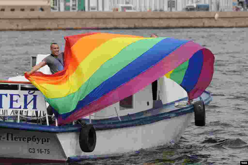 A gay-rights activist holds a rainbow flag onboard a motor boat during a gay-pride parade in St. Petersburg on June 25, 2011.