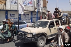 Taliban fighters drive an Afghan National Army vehicle through a street in Kandahar on August 13.