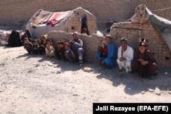 An internally displaced Afghan family outside a temporary shelter await relief from the authorities on the outskirts of Herat on June 15.