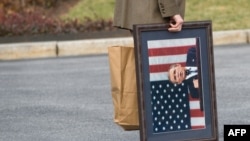 A White House staffer carries a framed photograph of President George W. Bush outside the the White House on January 13