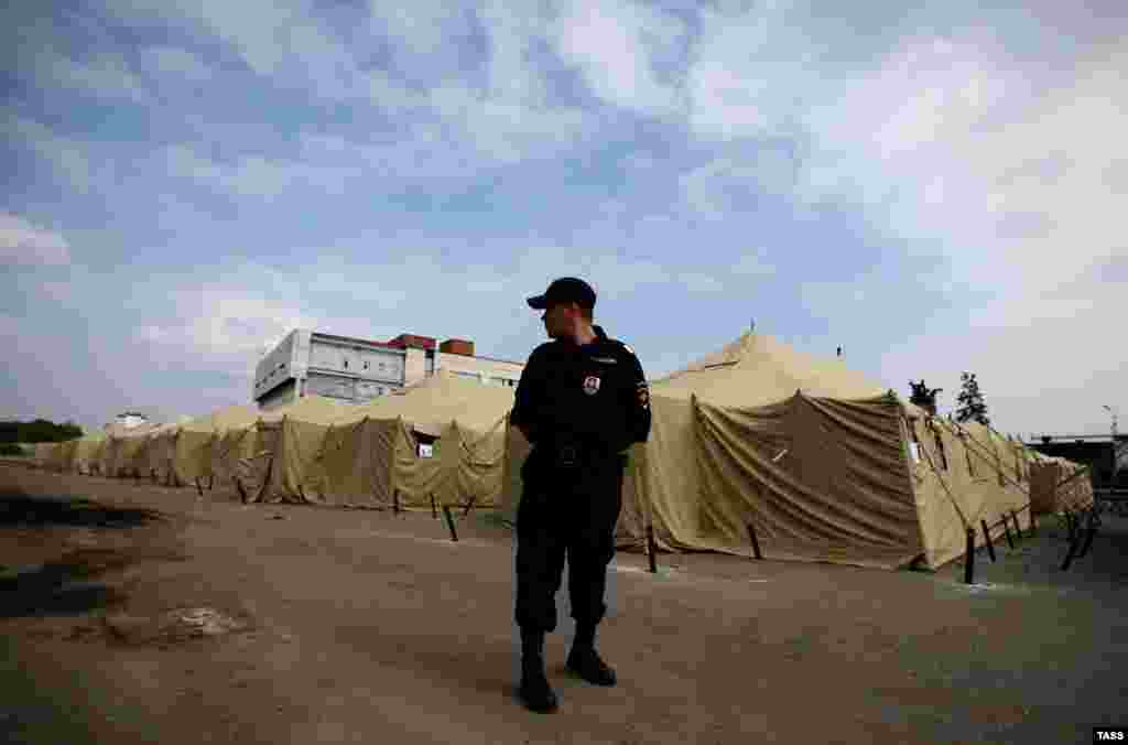 A Russian police officer stands guard at a tent camp for illegal migrant workers at the site of Moscow&#39;s former Cherkizovsky market in August. City authorities closed the market in 2009, alleging numerous illegal activities and safety violations. &nbsp;