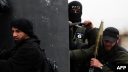 A Turkish fighter of the jihadist group Al-Nusra Front, bearing the flag of Al-Qaeda on his jacket (center), holds position with comrades in the village of Aziza, on the southern outskirts of Aleppo, in April.