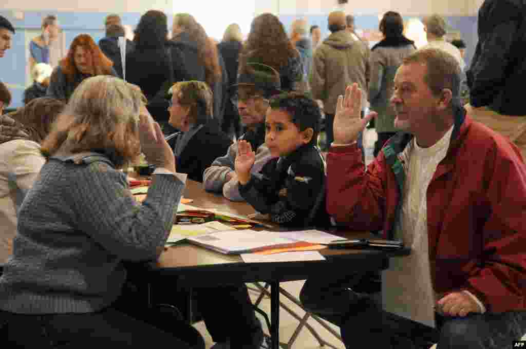 Tom Hoisington (right) raises his right hand after being registered to vote at the Bishop Leo O&#39;Neil Youth Center in Manchester, New Hampshire. Hoisington&#39;s grandson, Tonykus Hebert, mimics his grandfather.