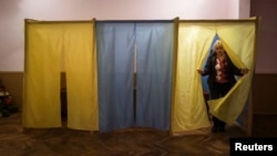 A staff member of a local community center, converted to a polling station, walks out of a voting booth in the Ukrainian village of Novotroits'ke, south of the pro-Russian rebels stronghold of Donetsk on October 23.