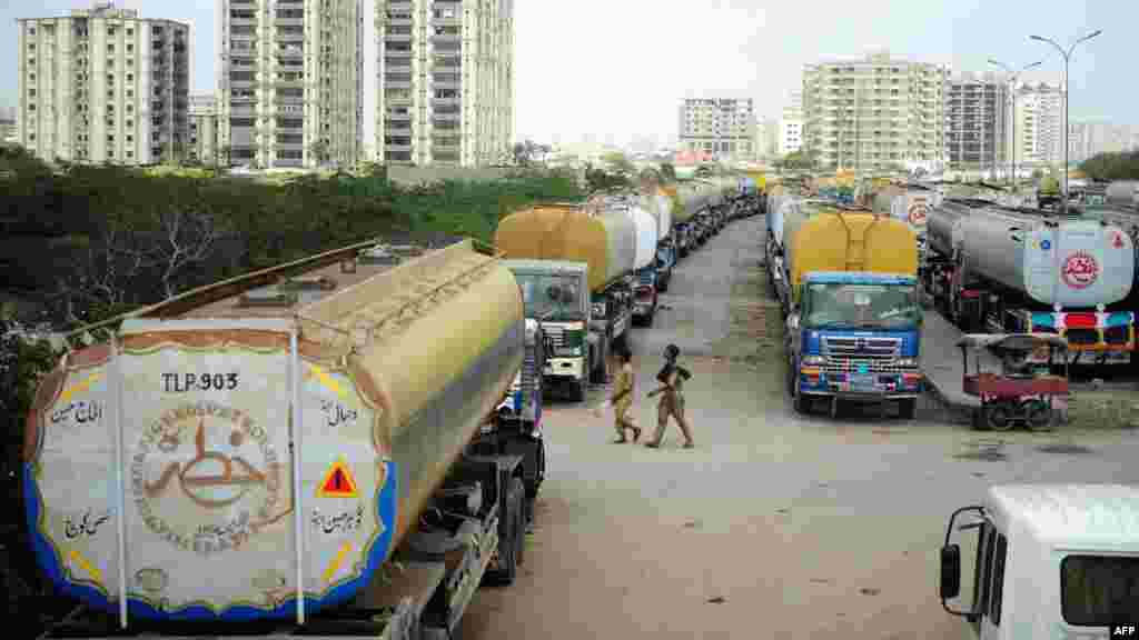 Men walk past fuel tankers, used to transport fuel to NATO forces in Afghanistan, parked near oil terminals in the Pakistani port city of Karachi.