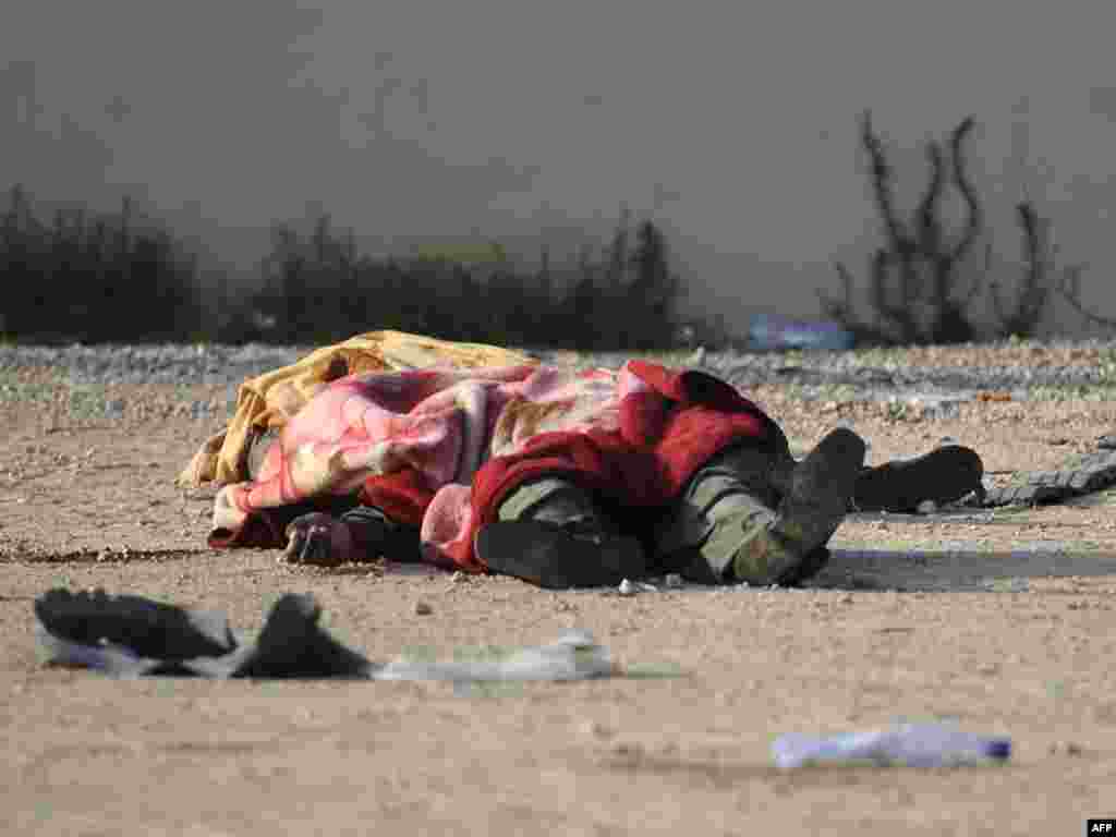 A dead combatant is covered with a blanket as he lies on a street in the Libyan capital.