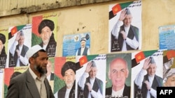 A man walks past posters of presidential candidates on a wall in Kabul.