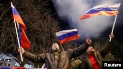 Pro-Russia activists in Donetsk react on the street as fireworks explode in the sky after Russian President Vladimir Putin signed a decree recognizing the two Russia-backed separatist regions in eastern Ukraine as independent entities.