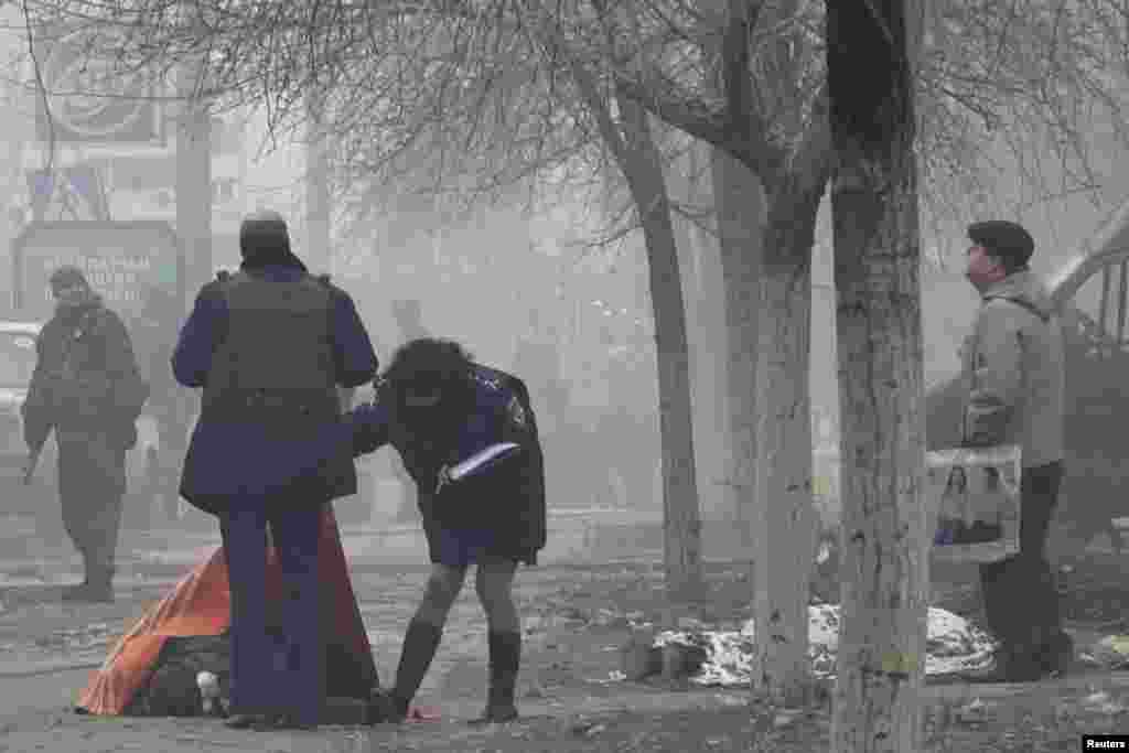 Police look at the body of a victim of shelling in Mariupol