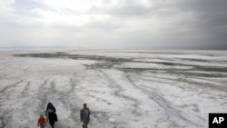 A family walks on the solidified salts of Lake Orumieh.