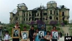 Children displaying photos of war victims stand in front of the damaged Darul Aman Palace just outside of Kabul, which was one of the area's many casualties, before its reconstruction.