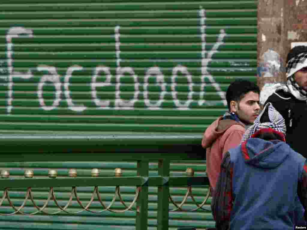 Opposition supporters talk near graffiti referring to the social networking site Facebook on Tahrir Square.