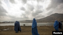 Burqa-clad women walk along a road in Kabul, where women continue to struggle for their rights.